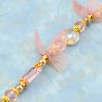 Bead strand for jewelry making featuring pink and tan glass beads and a pair of chiffon butterfly wings.