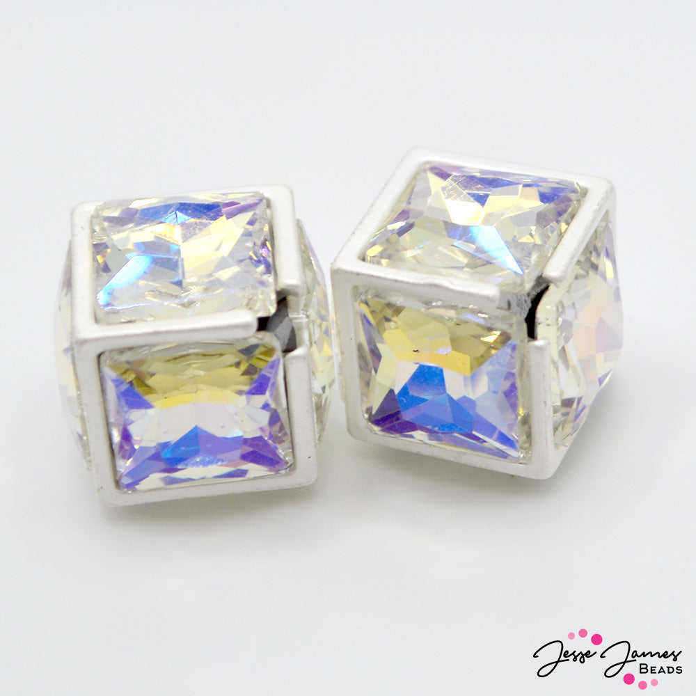 These sparkling focal beads feature a large AB Rhinestone center adorned by silver plated metal frames. These cube shaped beads sparkling when exposed to light, these focal crystals sparkle in shades of blue, purple, yellow, and green. Sold in a set of 2 beads. Measure 16mm.