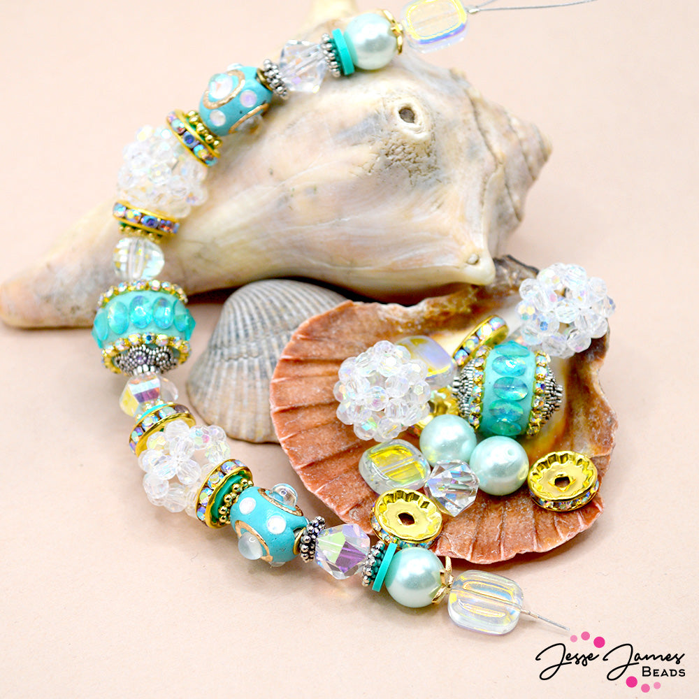 Embrace the magic of nature with our Be Jelly Bead Strand in Flower Hat Jelly. Let its vibrant colors and enchanting design transport you to a world of new jewelry-making possibilities! This teal-tastic strand features sparkling custom bohos, faux pearls, bright silver and gold metal spacers, and yellow-green coated glass. 7 inch strand. Largest bead on strand measures 16mm. Smallest bead on strand measures 8mm. 