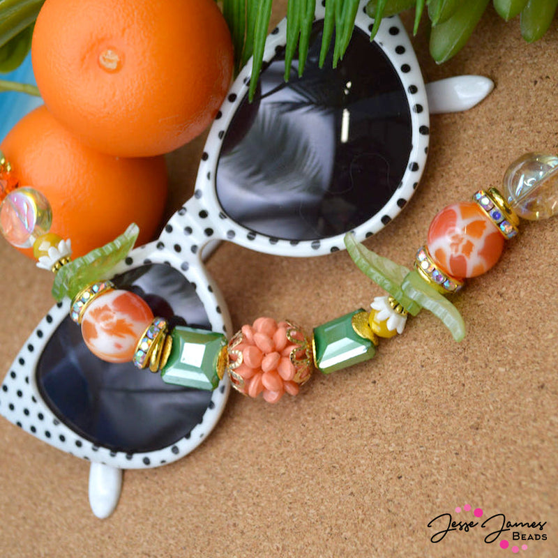 Step into the sun-dappled groves of Orange Grove with our charming Bead Strand collection, where each strand embodies the essence of citrus-scented charm and artistic expression. This 7 inch bead strand features juicy orange swirled glass beads adorned with glass leaves, faceted glass, and rhinestone spacers. Largest bead on strand measures 18mm x 15mm. Smallest bead measures 6mm.