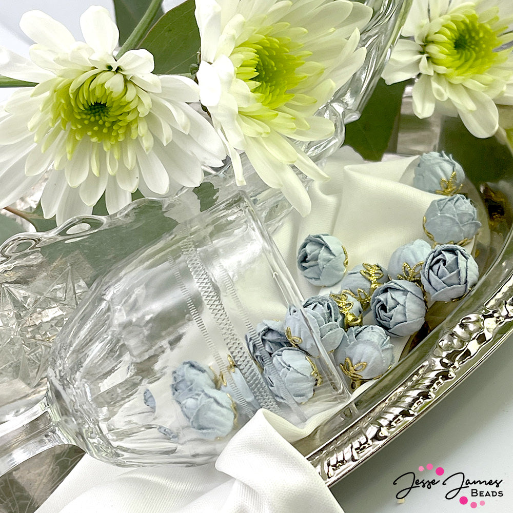 Create jewelry with an air of mystery. These light blue roses represent mystery, perfect for captivating your audience when added to jewelry creations. Each charm features a delicately folded rose perched on a bright gold-plated metal base of leaves. 2 Charms per set. Measure 15mm X 13mm.
