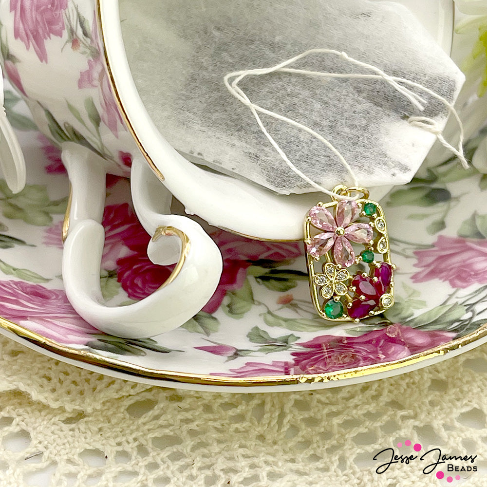 Prepare for a lovely vacation at your private Summer estate with this dazzling rhinestone pendant. This focal piece features a bright gold-plated metal base decorated with vibrant hues of pink, green, and crystal. The sparkle from this pendant is sure to turn heads when added to a necklace or bracelet. Pendant measures 22mm X 14mm X 3mm.