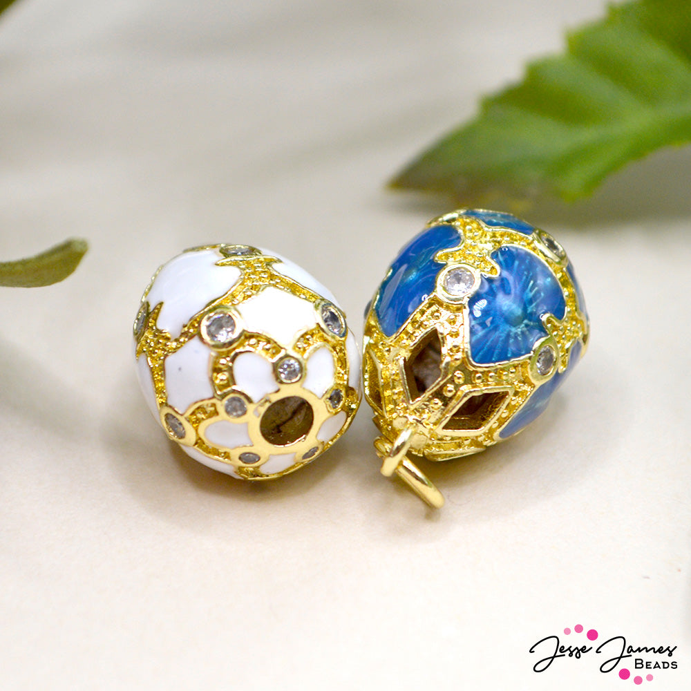 These elegant egg-shaped pendants feature bold gold-plated metal accented with rich enamel colors. Choose between our classic bright white or our enticing dark blue. Each pendant measures 20mm x 14mm. Features a 6mm jump ring for easy attachment to necklaces, bracelets, and more. 